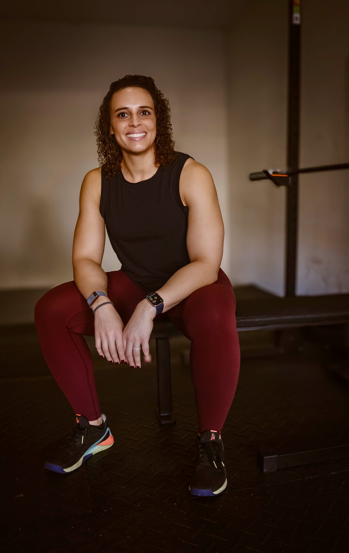 Allie Jackson seated on a bench in her home gym, smiling